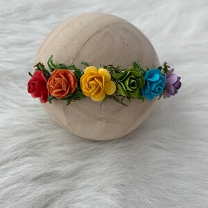 K&ouml;nnte beinhalten: Eine Regenbogen-Blumenkrone mit roten, orangen, gelben, gr&uuml;nen, blauen und violetten Filzblumen.