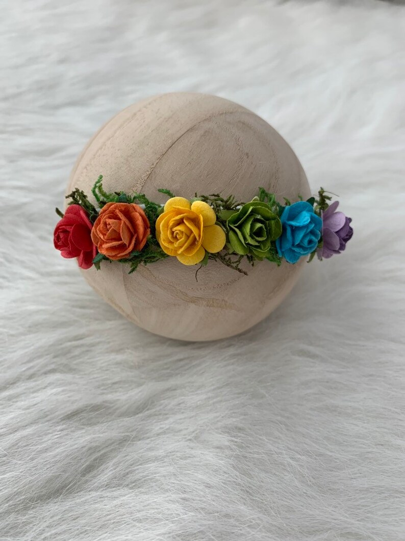 K&ouml;nnte beinhalten: Eine Regenbogen-Blumenkrone mit roten, orangen, gelben, gr&uuml;nen, blauen und violetten Filzblumen.