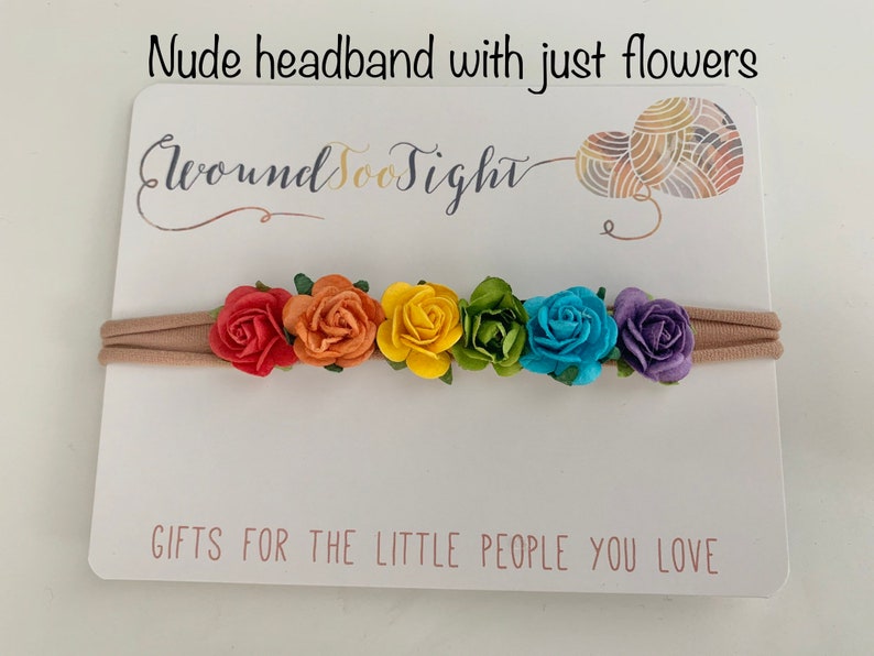 K&ouml;nnte beinhalten: Ein nacktes Stirnband mit einem Regenbogen aus Stoffblumen. Das Stirnband befindet sich auf einer wei&szlig;en Karte mit dem Text "Around Too Sight" und "Gifts for the little people you love".
