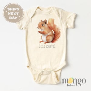 May include: A cream-colored baby onesie with a cute illustration of a brown squirrel with a bushy tail. The text "little squirrel" is printed below the squirrel.