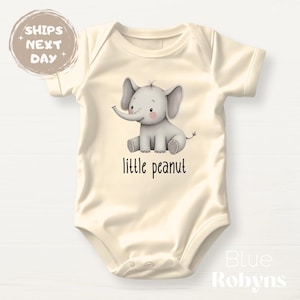 May include: A cream-colored baby onesie with a cute cartoon elephant illustration and the text "little peanut".