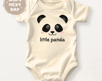 May include: A cream-colored baby onesie with a black and white panda face graphic and the text "little panda" printed on the front.