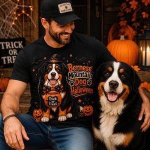 May include: A black t-shirt featuring a graphic of a Bernese Mountain Dog wearing a witch hat and a pumpkin-themed bowtie, holding a trick-or-treat bucket. The text reads Bernese Mountain Dog Halloween. The design includes orange pumpkins and bats.