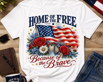May include: White t-shirt with a patriotic design featuring an American flag, red roses, and the text "HOME OF THE FREE BECAUSE OF THE BRAVE." The design includes blue and white floral accents and dog tags.