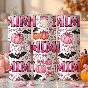 May include: A cylindrical tumbler with a white background featuring a repeating pattern of pink pumpkins, black bats, white ghosts, and pink bows. The word MIMI is printed in large, bold pink letters throughout the design, interspersed with small pink hearts.