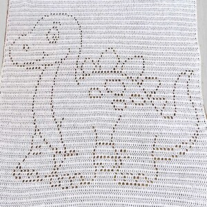 May include: White crocheted blanket with a dinosaur pattern. The blanket is rectangular and features a detailed dinosaur outline, with openwork detailing. The crochet is tight and even, creating a soft, textured surface, suitable for a baby.