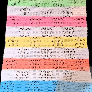 K&ouml;nnte beinhalten: Eine mehrfarbige H&auml;keldecke mit Streifen in Gr&uuml;n, Wei&szlig;, Rosa, Gelb, Orange und Blau. Jeder Streifen hat ein sich wiederholendes Muster aus kleinen, dunklen Formen. Die Decke ist wahrscheinlich aus weichem Garn gefertigt.