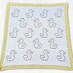 Può includere: Una coperta per neonati all'uncinetto con un centro azzurro chiaro con un motivo a silhouette di anatra. La coperta ha un bordo giallo. Il motivo dell'anatra è creato con piccoli fori all'uncinetto.