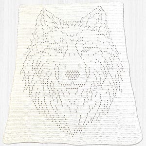 May include: A white crocheted blanket with a dog face design. The blanket is rectangular and appears handmade, with a textured surface and a clear outline of the dog's features. The blanket is likely made of cotton or a similar yarn.