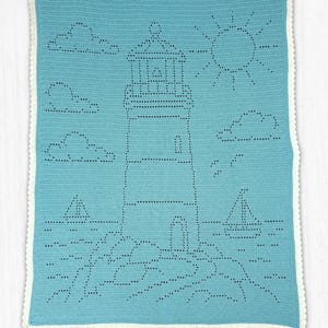 May include: A rectangular crochet blanket in light blue featuring a white scalloped border. The center displays a lighthouse design created with openwork stitches, surrounded by clouds, a sun, two sailboats, and rocky terrain at the base.