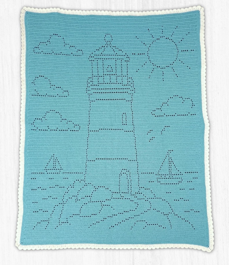 May include: A rectangular crochet blanket in light blue featuring a white scalloped border. The center displays a lighthouse design created with openwork stitches, surrounded by clouds, a sun, two sailboats, and rocky terrain at the base.
