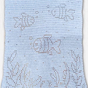 May include: A light blue crocheted blanket featuring a fish and floral design. The blanket is made of a soft, textured yarn and has a delicate, handmade appearance. The fish and floral patterns are created with openwork, adding visual interest.