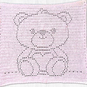 May include: A square, light pink crochet blanket featuring a dark pink, open-work bear silhouette design created with a filet crochet technique. The blanket has a consistent, textured stitch pattern throughout and a simple, finished border edge.