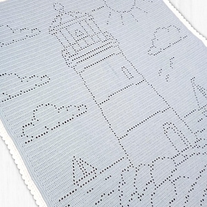 May include: A light blue crochet blanket featuring a detailed lighthouse design created with openwork stitches. The pattern includes a sun, clouds, and a sailboat, finished with a delicate white scalloped border along the entire rectangular edge.