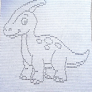 May include: A light blue crochet blanket featuring a dinosaur design. The dinosaur is outlined in dark blue stitches, creating a contrasting image against the lighter background. The blanket is rectangular and appears handmade.