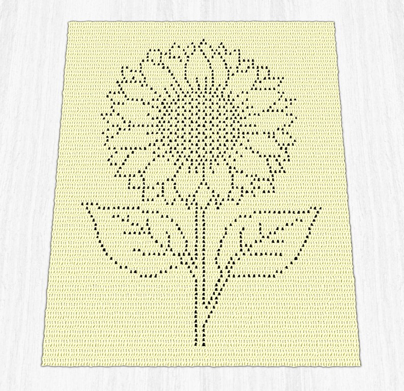 Puede incluir: Una manta rectangular de ganchillo color crema con un dise&ntilde;o gr&aacute;fico negro centrado de un gran girasol que presenta una cabeza circular detallada, un tallo central y dos hojas sim&eacute;tricas que se extienden desde la base.