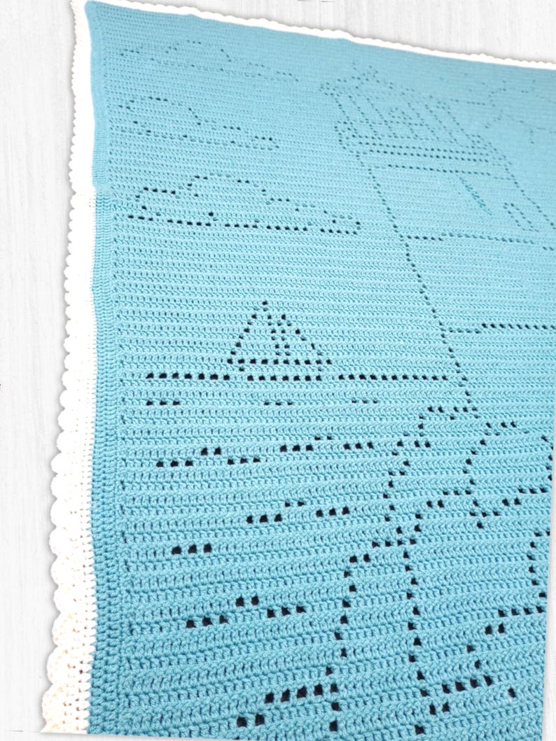 May include: A light blue crochet blanket featuring a lighthouse, a sailboat, and cloud motifs created with openwork stitches. The blanket is finished with a white scalloped border along the edge, showcasing a detailed nautical-themed pattern.