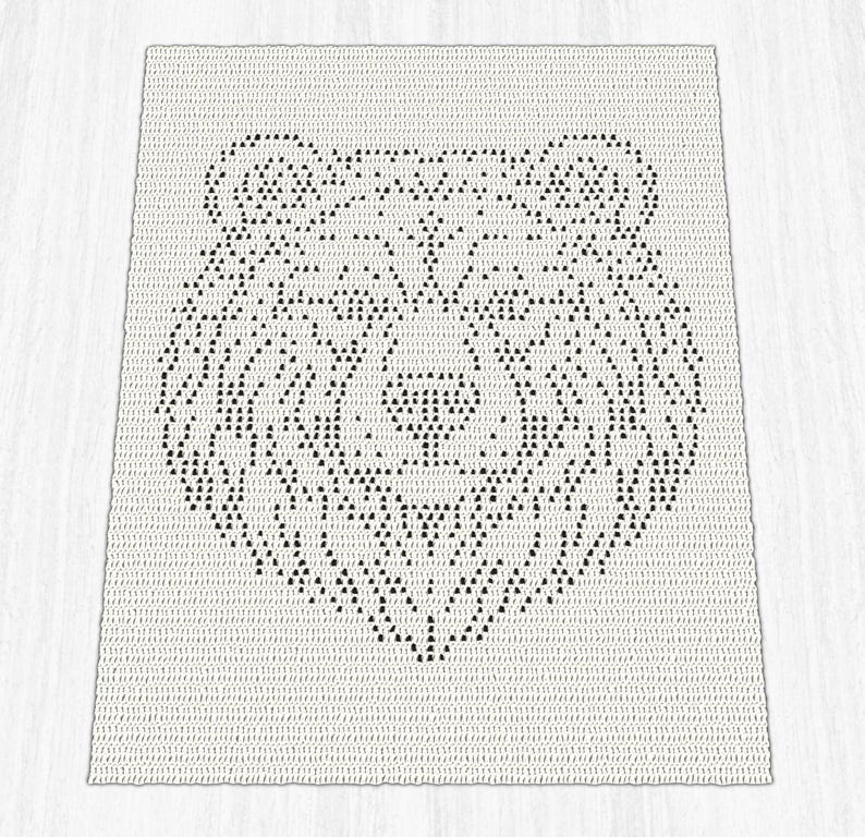 Pode incluir: Uma manta retangular de croch&ecirc; com fundo branco e um design geom&eacute;trico de cabe&ccedil;a de urso preto centralizado no meio. O urso &eacute; composto por pequenos pontos triangulares repetitivos que formam o contorno e os tra&ccedil;os faciais.