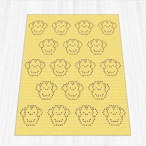 May include: A yellow crocheted blanket with a repeating pattern of smiling faces. The faces are made with brown yarn and are evenly spaced. The blanket is made of a soft, textured yarn. The blanket's dimensions are not visible.