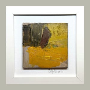 May include: Abstract oil painting in a white frame. The artwork features a textured composition with shades of yellow, brown, and green. The artist's signature, "Colette 2026," is visible in the lower right corner. The painting is square and mounted on a white canvas.