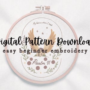 May include: A digital embroidery pattern download displayed in a round wooden hoop. The design features a central image of wings, a house, and the text "Psalm 91". The words "My God in whom I trust" are also included.