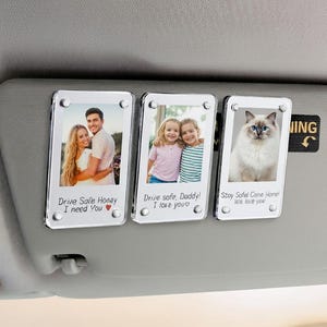 Puede incluir: Tres clips rectangulares para visera de coche con fotos y texto. Las fotos incluyen una pareja, dos niñas pequeñas y un gato. El texto incluye "Drive Safe Honey I need You", "Drive safe Daddy! I love you" y "Stay Safe Come Home! We love you".