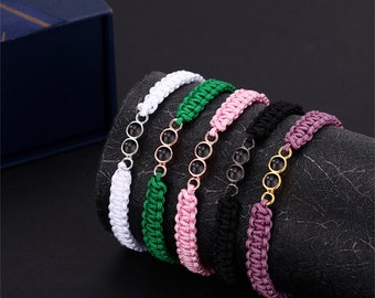 Op de afbeelding: Zes gevlochten armbanden met zwarte kralen en gouden accenten. De armbanden zijn in wit, groen, roze, zwart en paars.