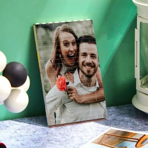 Peut inclure: Une mosa&iuml;que de photos d'un couple, un homme et une femme, souriant et regardant la cam&eacute;ra. La femme tient une fleur rouge. La photo est imprim&eacute;e sur un fond blanc.