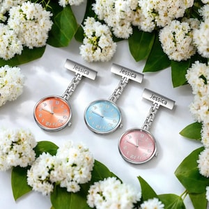 May include: Three silver-toned pocket watches with a chain and a clip. Each watch has a different colored face: orange, blue, and pink. The clip has a personalized name tag that reads "Jessica".