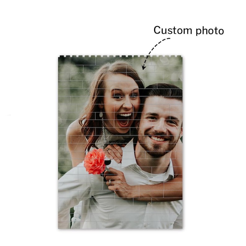 Peut inclure: Un couple sourit et rit en posant pour une photo. La femme porte une robe blanche et tient une fleur rose. L'homme porte une chemise blanche et a son bras autour de la taille de la femme.