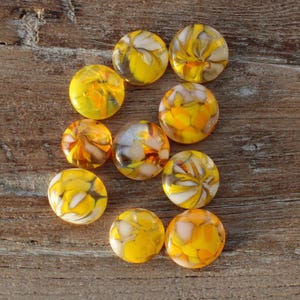 Peut inclure: Dix cabochons ronds en verre avec des motifs en spirale jaunes et blancs. Les cabochons mesurent environ 2,5 cm de diamètre.