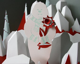 Puede incluir: Un muñeco de nieve de papel blanco sosteniendo una flor de papel roja con un tallo verde. El muñeco de nieve lleva una bufanda azul claro con un patrón blanco y verde. El fondo es un paisaje de papel blanco y rojo.