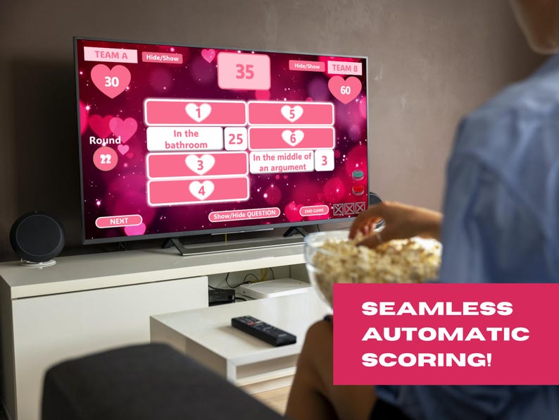 May include: A television screen displaying a game show with a pink and white background. The game show is called "Round 22" and features questions about relationships. The screen also shows the scores for two teams, Team A with 30 points and Team B with 60 points. The text "SEAMLESS AUTOMATIC SCORING!" is displayed in a pink box at the bottom of the screen.
