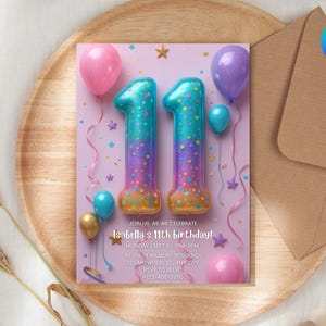 Puede incluir: Una tarjeta de invitación de cumpleaños con el número "11" en forma de globo, rodeado de globos y estrellas. La tarjeta es de color lila claro con el texto "Isabella's 11th birthday!" y detalles del evento. La invitación está sobre una bandeja de madera.
