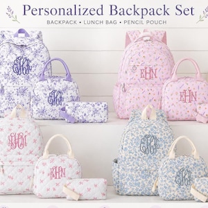 May include: A personalized backpack set featuring a backpack, lunch bag, and pencil pouch in four floral patterns: purple, pink, white with pink, and blue. Each item displays a monogrammed initial design. The text reads Personalized Backpack Set.