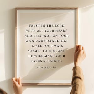 May include: A framed print with the text "TRUST IN THE LORD WITH ALL YOUR HEART AND LEAN NOT ON YOUR OWN UNDERSTANDING; IN ALL YOUR WAYS SUBMIT TO HIM, AND HE WILL MAKE YOUR PATHS STRAIGHT." The text is in black, with the Bible verse Proverbs 3:5-6.