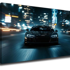 May include: A canvas print of a black sports car speeding down a road at night. The car's headlights and taillights are illuminated, and the background features blurred city lights. The car is an Audi.