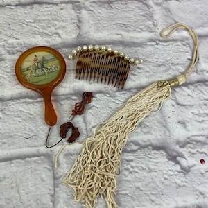 May include: A set of vintage hair accessories including a brown tortoise shell comb with pearl accents, a small brown hand mirror with a hunting scene and the text "Frankfort, Ky." on the back, and two brown hair clips.