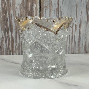 May include: A clear glass sugar bowl with a gold rim and a cut glass design.