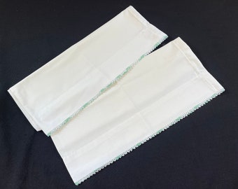 May include: Two white pillowcases with a green crocheted trim.