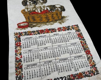 Cesta de toallas con calendario de lino vintage de 1973 con diseño de cachorros.