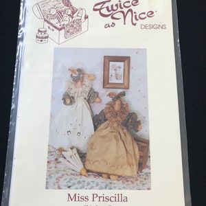 May include: Twice as Nice Designs doll pattern, Miss Priscilla, 12 inches tall, No. 178. The pattern shows two dolls, one in a white dress and the other in a brown dress, both with lace trim. The dolls are standing on a patterned fabric.