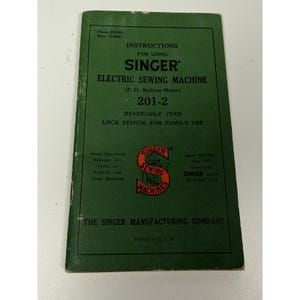 Könnte beinhalten: Eine grüne Bedienungsanleitung für eine elektrische Singer Nähmaschine Modell 201-2. Das Cover zeigt schwarzen Text, ein rotes und schwarzes Singer-Logo sowie den Text Form 20340 Rev. (1055). Es enthält Details zum Steppstich.