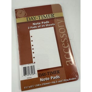 May include: A Day-Timer brand note pad accessory. The pad is brown with white lined paper and pre-punched holes. The packaging reads "Note Pads 2 Pads of 24 Sheets" and "5 1/2" x 8 1/2" Fits 3- and 7-Ring Binders".