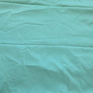 K&ouml;nnte beinhalten: Ein hellblauer Stoff mit glatter Textur. Der Stoff ist gefaltet und hat einen leichten Glanz.