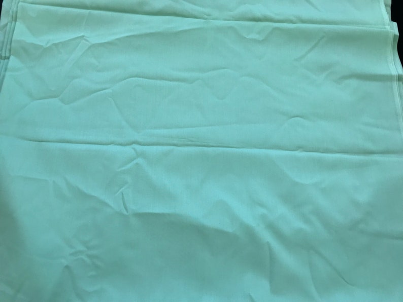 K&ouml;nnte beinhalten: Ein hellblauer Stoff mit glatter Textur. Der Stoff ist gefaltet und hat einen leichten Glanz.