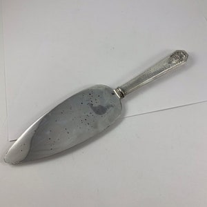 May include: Silver cake server with a hammered handle and a decorative design at the end of the handle.