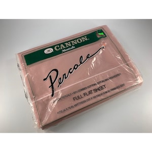 Puede incluir: Una sábana plana completa Cannon Percale rosa en su embalaje original. El embalaje incluye el logotipo de Cannon, la palabra "Percale" en cursiva y texto que indica que la sábana se adapta a un colchón de 137 x 193 cm.