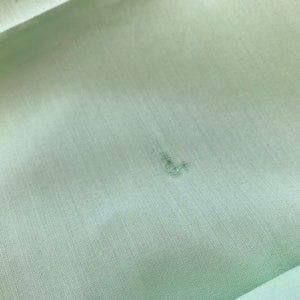 K&ouml;nnte beinhalten: Ein hellgr&uuml;ner Stoff mit einem kleinen, dunklen Fleck in der Mitte.