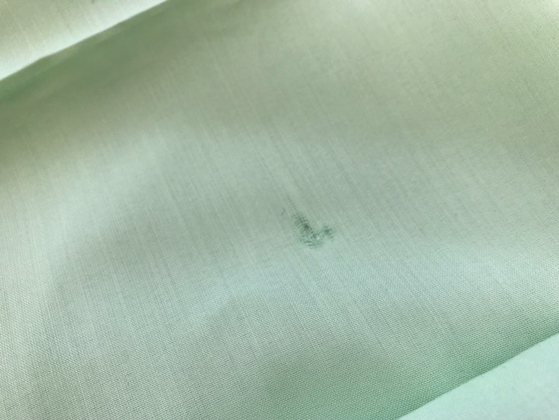 K&ouml;nnte beinhalten: Ein hellgr&uuml;ner Stoff mit einem kleinen, dunklen Fleck in der Mitte.